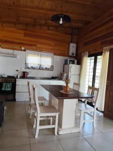 a kitchen with a table and chairs in a room at Los Grillos Cabañas Serranas in Los Reartes