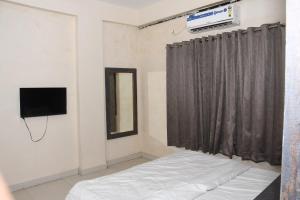 a bedroom with a bed and a tv and a curtain at Manas homes in Gwalior +60 photos