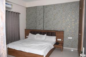 a bedroom with a bed and a wall with wallpaper at Manas homes in Gwalior