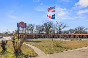 a us flag and a sign in front of a school at Western Inn by Capital O Cleburne TX in Cleburne