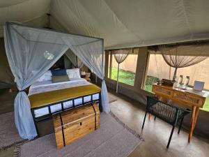 a bedroom with a tent with a bed and a desk at Kampasi Olmoingo Camp in Talek