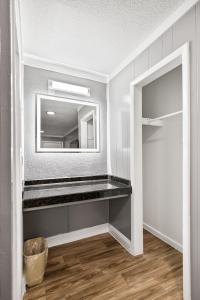 a bathroom with a mirror on the wall and a shelf at Western Inn by Capital O Cleburne TX in Cleburne +36 photos