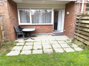 a patio with a table and a chair in front of a building at Strandmuschel in Norddeich