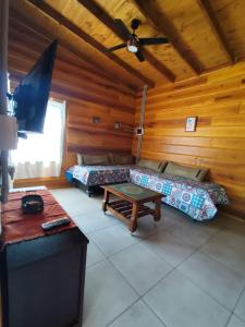 a room with two beds and a table in a cabin at Los Grillos Cabañas Serranas in Los Reartes