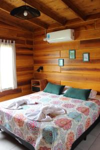 a bedroom with a bed in a room with wooden walls at Los Grillos Cabañas Serranas in Los Reartes +14 photos