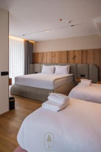 une chambre d'hôtel avec trois lits aux draps blancs dans l'établissement Pine Hotel & Spa Brezovice, à Brezovicë