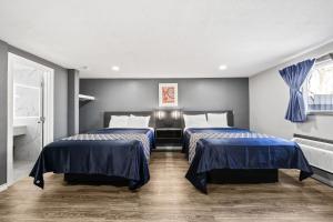 two beds in a room with blue walls at Western Inn by Capital O Cleburne TX in Cleburne