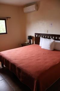 a bedroom with a bed with a red blanket and a window at Hotel El Cafetalero in Xicotepec de Juárez