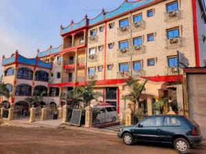 a car parked in front of a large building at lynna hôtel in Yaoundé