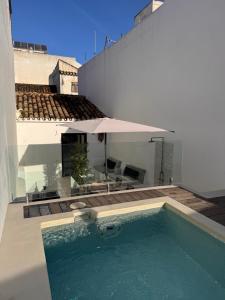 a swimming pool with an umbrella next to a building at Unique Townhouse with rooftop pool in Estepona
