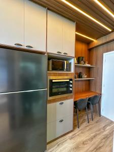 a kitchen with a stainless steel refrigerator and a table at Studio Moderno e Completo in Aracaju +7 photos