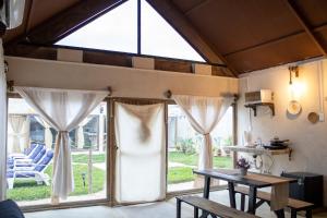 ein Raum mit großen Fenstern und einem Tisch und Stühlen in der Unterkunft Cabañas Tzikin, Telchac Puerto in Telchac