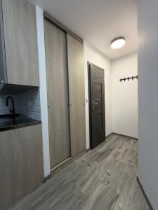 an empty room with a kitchen with wooden cabinets at Apartament Hexagon nr 36 in Grzybowo