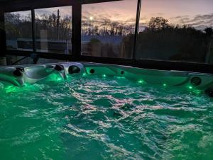 a jacuzzi tub with green lights in a house at Villa Argonne - Cottages & Spa Privatif in Ouville-la-Rivière