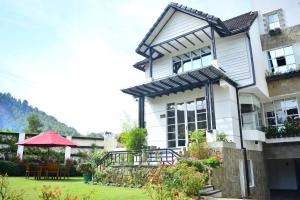 una casa blanca con un jardín delante de ella en Unique Cottages en Nuwara Eliya