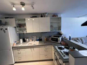 a kitchen with white cabinets and a white refrigerator at Boutique in Rothschild in Rishon LeẔiyyon
