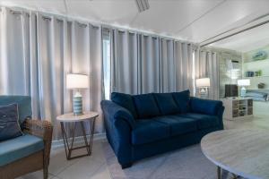 a living room with a blue couch and a table at Cozy Conch Cottage in Cudjoe Key