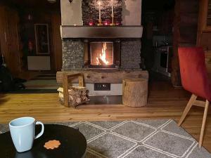 a fireplace in a living room with a table and a coffee cup at Holiday Home Ylläspollu a by Interhome in Ylläsjärvi
