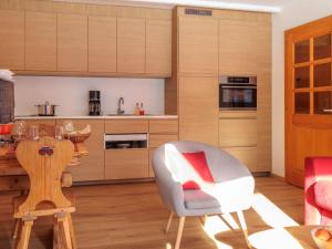 a kitchen with wooden cabinets and a table and a chair at Apartment Ecluses 2 by Interhome in Nendaz +24 photos
