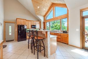 a kitchen with wooden cabinets and a island with bar stools at Rocky Mountain Lodge by Railey Vacations in McHenry
