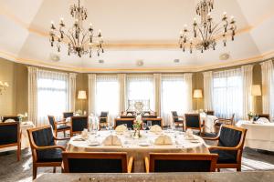 a dining room with tables and chairs and chandeliers at Schloß-Hotel Petry in Treis-Karden