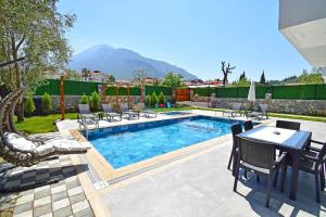 a swimming pool with a table and chairs next to it at Villa Olivin in Fethiye