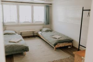 two beds in a room with two windows at 4 bedroom house for 8 guests in Brülisau