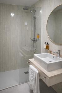 a bathroom with a sink and a shower and a tub at Hotel Zenite in Angra do Heroísmo
