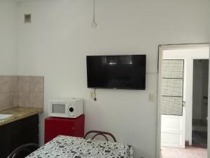 a kitchen with a table and a television on a wall at Casa Centrica 5 Huésped in Pinamar