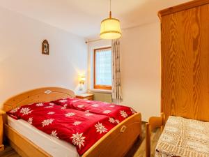a bedroom with a bed with a red blanket at Apartment Cristina by Interhome in Campestrin