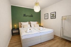 a large white bed in a room with a green wall at NAMASTÉ Homes - Ferienwohnungen - Altstadt - 2 Schlafzimmer in Bad Windsheim