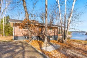 a brick house with trees in front of a lake at Lakeside Brick Retreat For 8 in Branson West