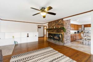 a living room with a fireplace and a ceiling fan at Lakeside Brick Retreat For 8 in Branson West +16 photos