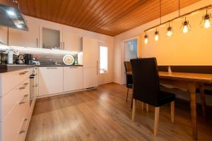 a kitchen with a wooden table and a black chair at Alpenwohnung "Zum Schorschi" mit Bergblick I voll ausgestattet I ruhige Lage in Oberammergau