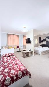 a bedroom with two beds and a flat screen tv at Sultan Saray in Türkistan