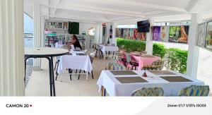 a restaurant with tables and chairs and a woman in the background at Hôtel Kolou Wyam in Tcharé