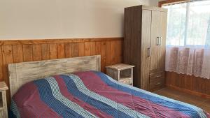 a bedroom with a bed with a colorful blanket on it at Rukas Huinkaray in Pucón