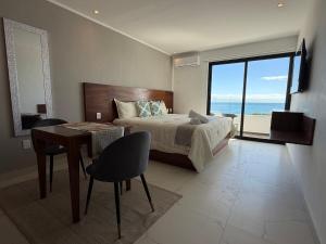a bedroom with a bed and a table and a view of the ocean at MIRAMARE Ocean View in Puerto Morelos