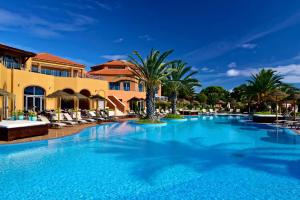 uma piscina num resort com cadeiras e palmeiras em Pestana Porto Santo Beach Resort & SPA em Porto Santo
