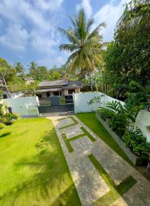 a garden with a house and a grass yard at THC - Tropical Hideaway Ceylon in Talpe