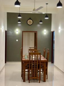 a dining room table with chairs and a clock on the wall at THC - Tropical Hideaway Ceylon in Talpe