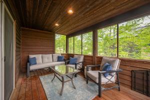 a screened in porch with a couch and chairs and a table at Chubby Bunny Lodge by Railey Vacations in McHenry