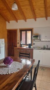 a kitchen with a wooden table with chairs in it at Cabañas Bachmann in Puerto Varas +10 photos