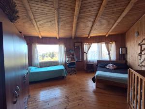 a bedroom with two beds in a room with wooden ceilings at Casacerrolacruz in Pichilemu