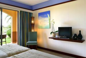 a bedroom with a bed and a television on a shelf at Pestana Porto Santo Beach Resort & SPA in Porto Santo