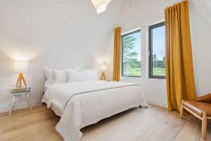 a white bedroom with a large bed and a window at Lake Bomoseen - Lake Access, Fire Pit & BBQ in Castleton