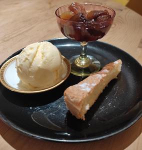 a black plate with a piece of cake and ice cream at Le Logis du Pradet in Moncrabeau