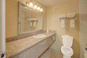 a bathroom with a toilet and a sink and a mirror at Capital O Duncanville Tx in Duncanville +18 photos