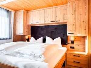 a bedroom with a large white bed with wooden walls at 1210 Apartments Benglerwald in Bach
