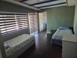 a bedroom with two beds in a room with windows at Cabañas de Turismo Berolav7 in Puerto Montt
